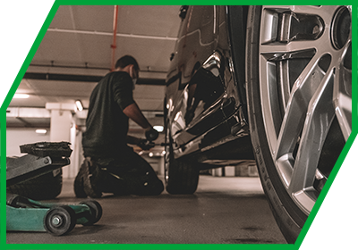 Person kniend vor Autoreifen zum Räderwechsel Person kniend vor Autoreifen zum saisonalen Räderwechsel